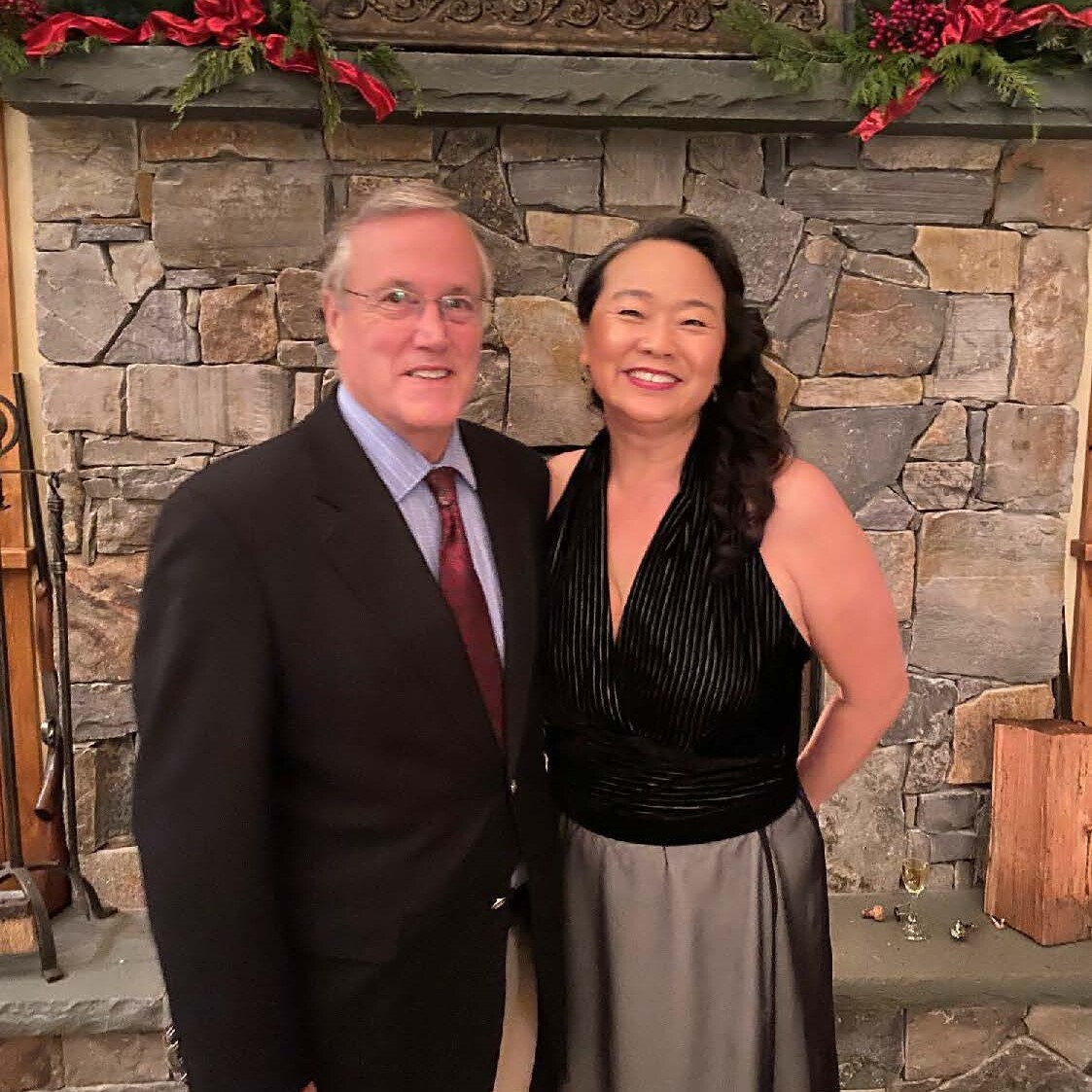 James and wife next to a stone fireplace